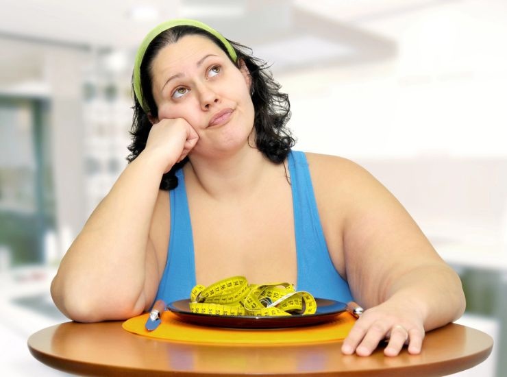 Donna in sovrappeso seduta a tavola, con metro nel piatto 
