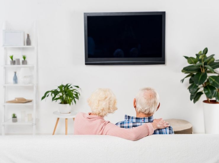 Anziani guardano la TV dal divano di casa