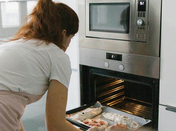 Donna impegnata nella preparazione di un piatto con il forno