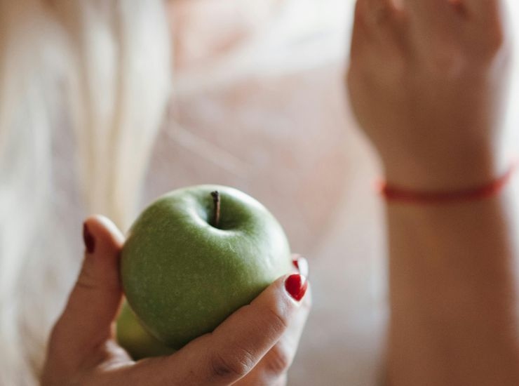 Mela verde in mano a una donna