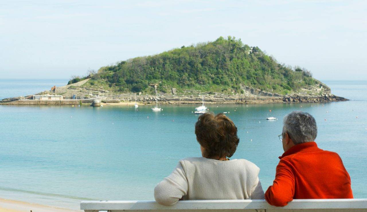 Uomo e donna anziani seduti su una panchina davanti al mare