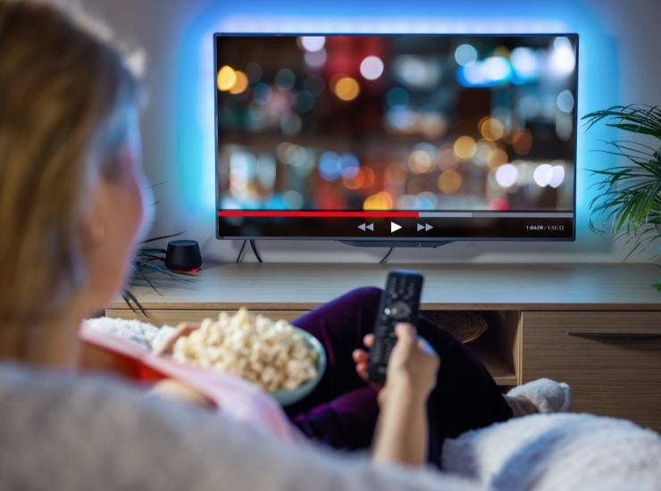 Donna sul divano con popcorn e televisione