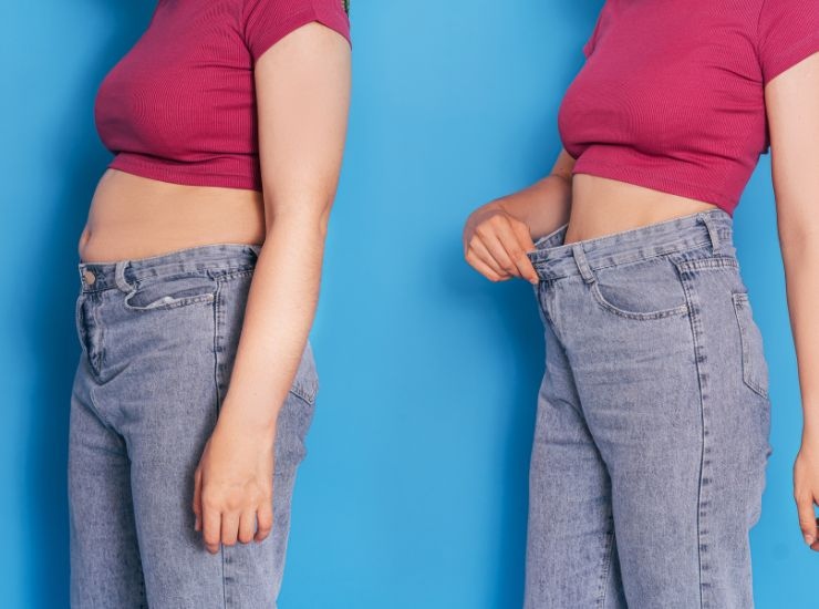 Ragazza che mostra la sua perdita di peso con i jeans che le vanno più larghi