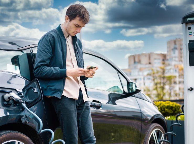 Ragazzo appostato alla colonnina di ricarica per auto elettrica