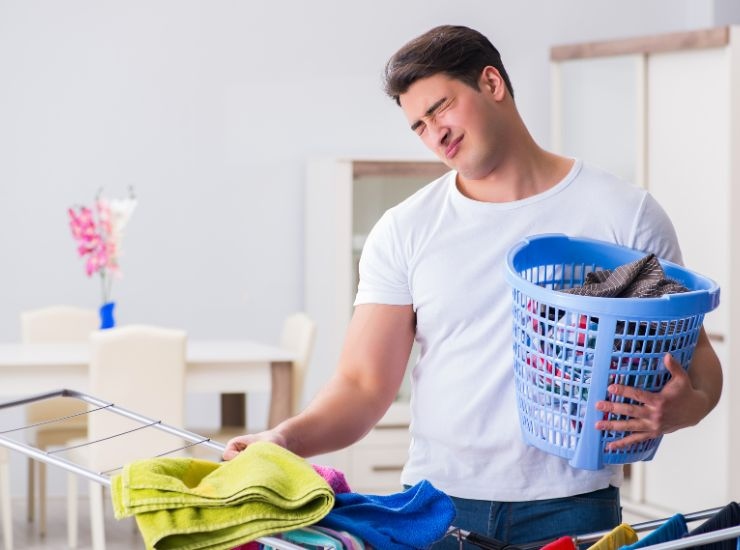 Uomo che stende bucato in casa