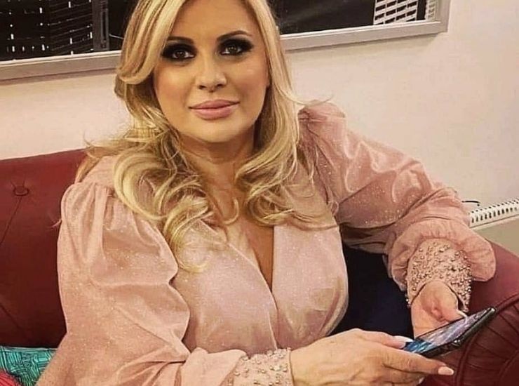 Tina Cipollari con un vestito rosa antico e cellulare in mano